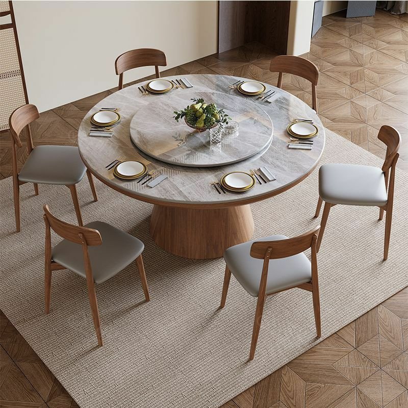 Table à manger ronde moderne en bois avec un plateau en pierre frittée et un plateau tournant central (type Lazy Susan), accompagnée de six chaises assorties au dossier incurvé et à l'assise grise.